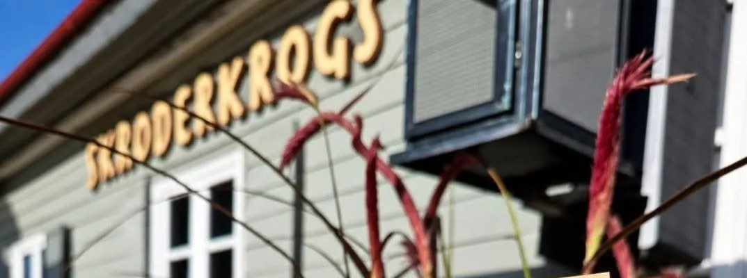 Skroderkroga fasāde ar zelta burtiem „Skroderkrogs” pret zilām debesīm